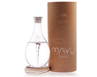 May include: A clear glass bottle with a swirling vortex of water inside. The bottle is on a wooden base and has a cork stopper. The bottle is labeled "MAYU SWIRL" and is packaged in a brown cardboard box with the words "Inspired by nature. Backed by science." printed on it.