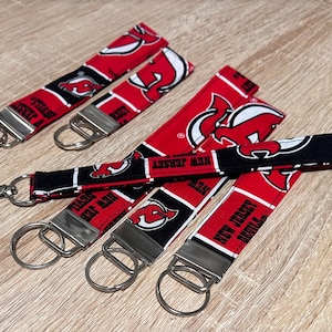 May include: Five red, white, and black keychains with a New Jersey Devils logo and the text "New Jersey Devils".