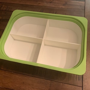 May include: A green plastic container with four compartments. The container is empty and has a white interior.