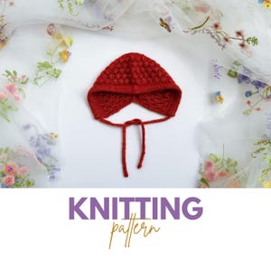 Puede incluir: Gorrito de bebé de punto rojo con un lazo. El gorro tiene un patrón texturizado y está fotografiado sobre un fondo blanco.