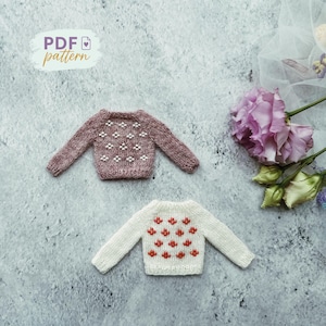 May include: Two miniature knitted sweaters. One is mauve with white diamond patterns, the other is white with red floral patterns. The image includes the text "PDF pattern".