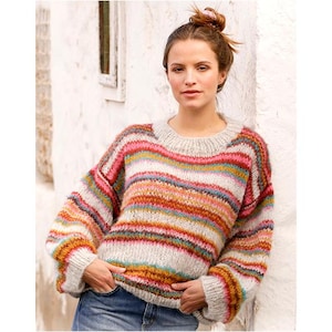 Könnte beinhalten: Ein übergroßer Pullover mit horizontalen Streifen in verschiedenen Farben, darunter Rosa, Orange, Gelb und Blau. Der Pullover hat einen runden Ausschnitt und lange Ärmel. Das Model trägt eine blaue Jeans.