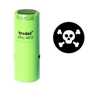 May include: A lime green self-inking stamp with the text "trodat printy 4612". The stamp imprint is a black circle with a white skull and crossbones design.