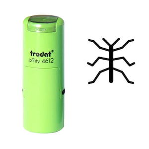 Op de afbeelding: Een lichtgroene Trodat printy 4612 stempel met een zwart insectenontwerp. De stempel heeft een doorzichtige plastic dop en een rechthoekig ontwerp. Het insectenontwerp is een eenvoudige, geometrische weergave.