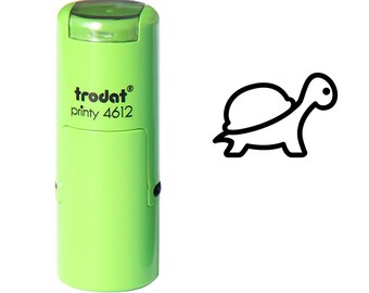 May include: A light green self-inking stamp with the text "trodat printy 4612" and a black outline of a turtle. The stamp is on a white background. The turtle design is simple and modern.