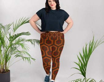 May include: A woman wearing a dark blue cropped t-shirt and leggings with a geometric pattern in shades of orange and brown. The leggings feature a repeating pattern of interlocking shapes.