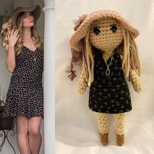 Può includere: Una bambola all'uncinetto con lunghi capelli biondi che indossa un cappello marrone e un vestito a pois neri e bianchi. La bambola indossa un anello d'oro su ogni dito.