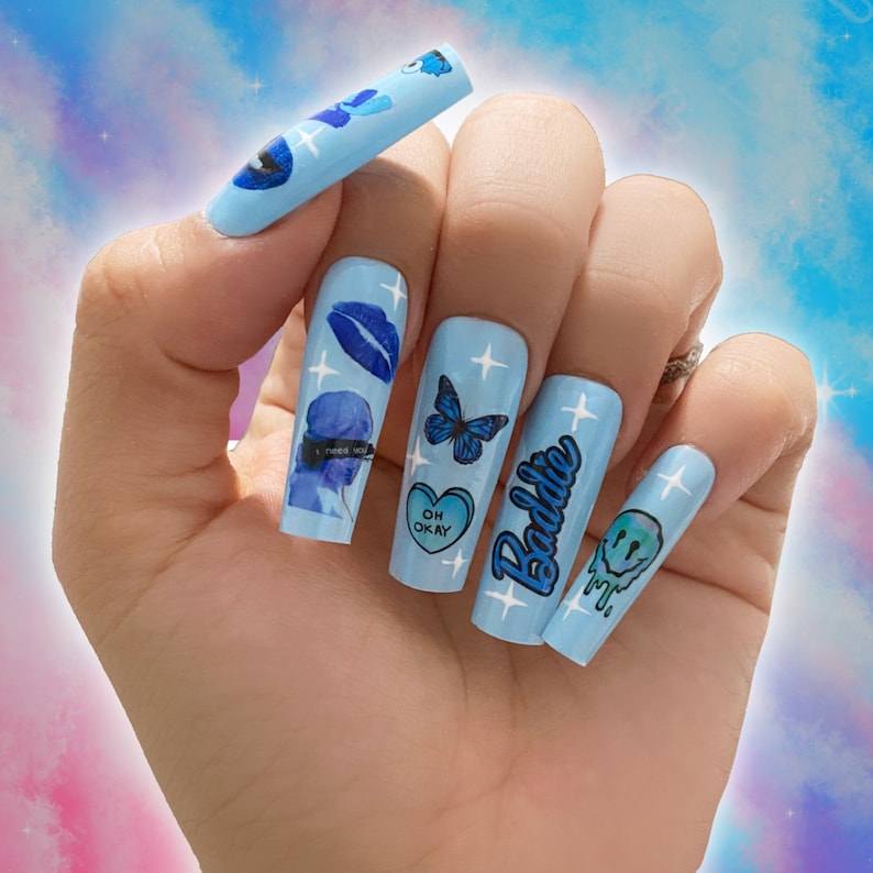 May include: Blue and white long acrylic nails with various designs including a butterfly, a heart with the text "Oh Okay", a smiley face, and the text "Baddie".