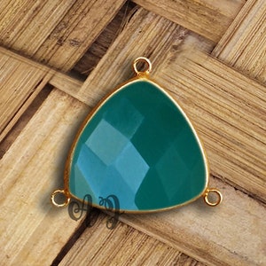 Peut inclure: Un pendentif triangulaire en pierre précieuse verte avec des accents en métal doré. Le pendentif a trois boucles pour l'attacher à une chaîne ou un cordon.