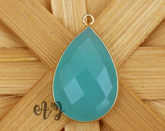 May include: A teardrop-shaped pendant with a light blue gemstone set in gold.