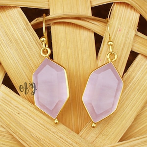 May include: A pair of gold earrings with light pink gemstone drops. The gemstones are faceted and have a hexagonal shape.
