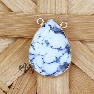 May include: White and black teardrop-shaped pendant with gold-toned metal bail. The pendant is made of natural stone with a marbled pattern.