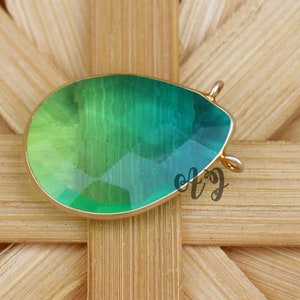 May include: A teardrop-shaped green and yellow gemstone pendant with a gold-toned bail.