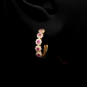 May include: Gold hoop earrings with a row of small red gemstones and white diamonds.