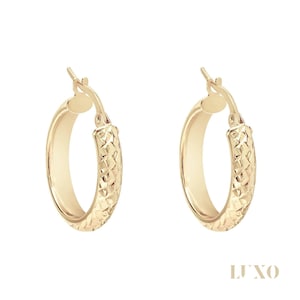 May include: A pair of gold-colored hoop earrings. The earrings have a textured, diamond-like pattern on the outer surface and a smooth inner surface. The word "LUXO" is printed in the bottom right corner.