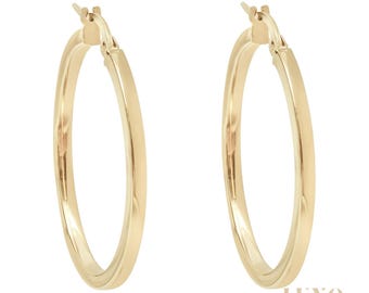 May include: A pair of polished gold hoop earrings with a smooth, rounded surface and a hinged post closure mechanism. The earrings feature a classic circular design with a reflective metallic finish, showcasing a simple and clean aesthetic.