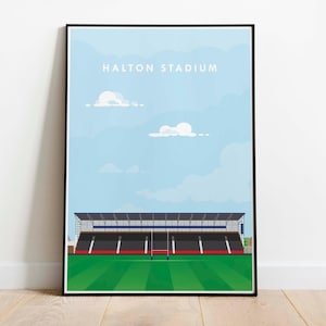 Può includere: Una stampa artistica incorniciata con lo stadio Halton sotto un cielo azzurro chiaro con nuvole bianche. Lo stadio ha un campo verde, posti a sedere neri e un bordo rosso. Le parole "HALTON STADIUM" sono stampate in alto.