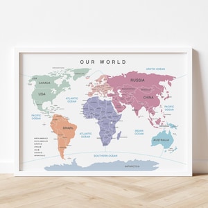 以下が含まれることがあります： 「OUR WORLD」のタイトルが付いた、額入りの世界地図プリント。 地図は、緑、ピンク、オレンジ、青など様々な色で国を表示し、海の名前も記載。 フレームは白です。