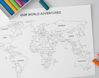 May include: A black and white world map with the text "OUR WORLD ADVENTURES" is displayed. A tray of colorful chalks in shades of orange, yellow, green, pink, and blue sits in the upper left corner. A single teal chalk is next to the map.