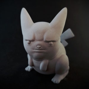 May include: A white 3D printed figurine of a cartoon character with a grumpy expression. The character has large ears, a round body, and a short tail.