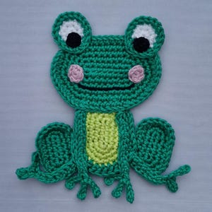 May include: Green crocheted frog applique with white eyes, black pupils, pink cheeks, and a yellow belly.