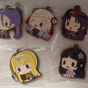 May include: Five anime character keychains. Each keychain features a different character with large eyes and colorful hair. The keychains are in clear plastic packaging and have a silver chain attached for hanging.