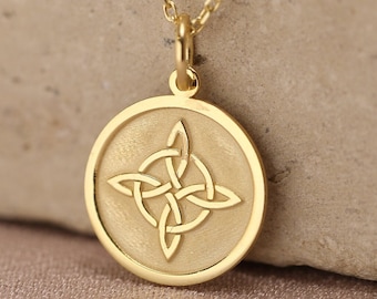 Op de afbeelding: Een gouden ketting met een ronde hanger met een matte afwerking en een gepolijste rand. Het midden van de hanger toont een gegraveerd vierpuntig Keltisch knoopontwerp. De hanger hangt aan een fijne gouden ketting met kleine schakels.