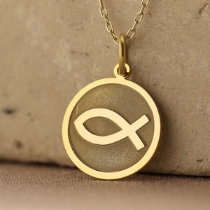 Puede incluir: Un collar de cadena de oro con un colgante redondo que presenta un símbolo Ichthys dorado.
