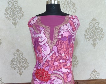 May include: A pink and gold embroidered dress with a floral pattern. The dress is on a mannequin and has a V-neckline.