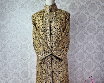 May include: A long, black and gold embroidered coat with a mandarin collar and button closure. The coat features intricate floral patterns and is displayed on a wooden mannequin. The garment is a traditional style.
