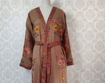 May include: A long brown robe with a floral embroidery design. The robe has a V-neckline and a tie belt. The embroidery features pink, red, yellow, and green flowers.