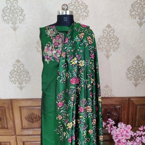 May include: A green embroidered dress with a floral pattern. The dress is on a mannequin and has a matching shawl.