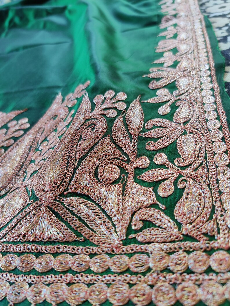 May include: Green fabric with intricate gold and silver embroidery. The embroidery features a floral design with leaves and swirls.