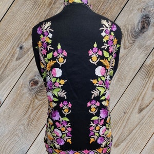 May include: Black shawl with colorful floral embroidery. The embroidery features pink, purple, white, yellow, and green flowers.