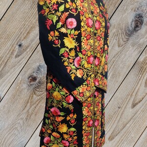 May include: A black long-sleeved jacket with intricate floral embroidery in shades of red, orange, yellow, and green. The embroidery is detailed and covers the entire jacket.