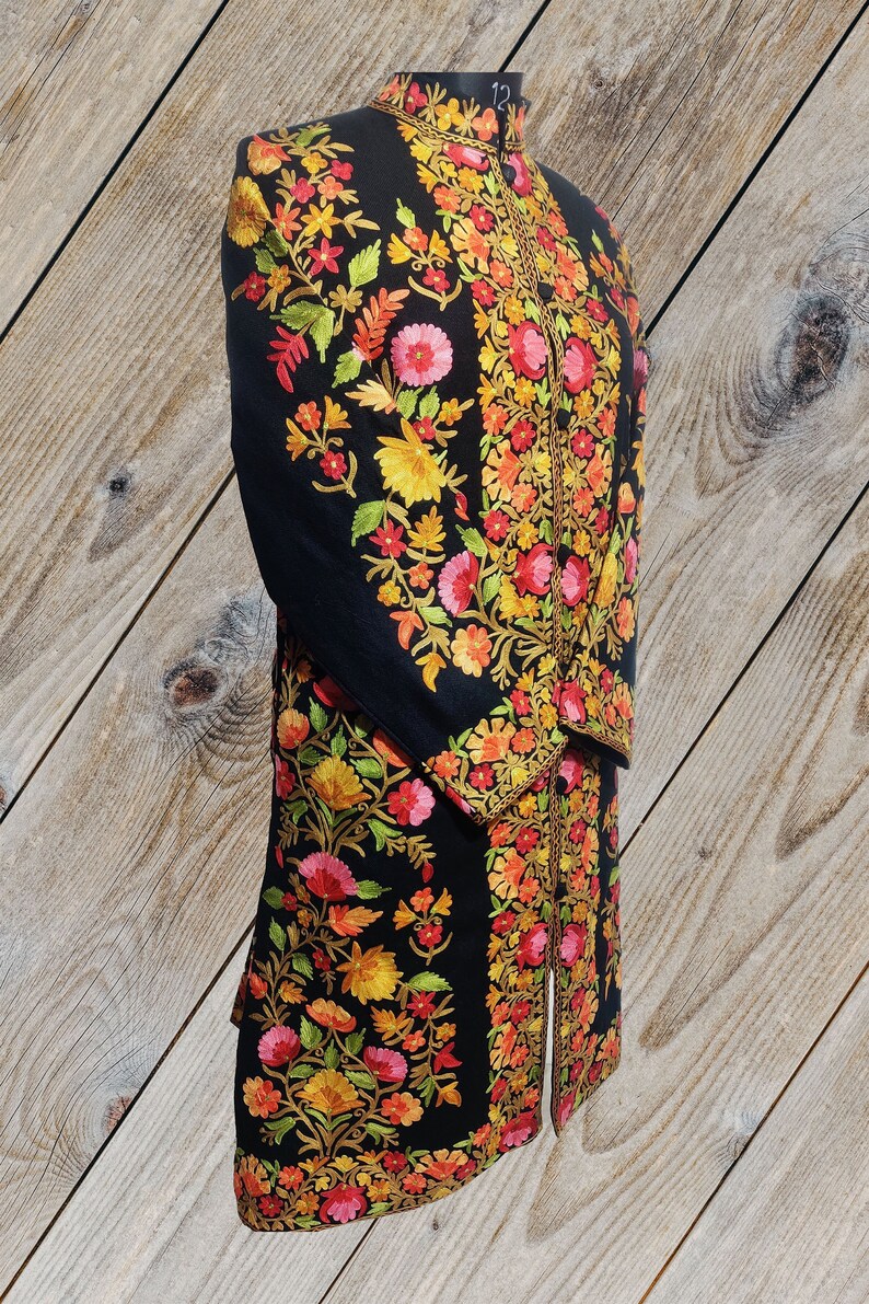 May include: A black long-sleeved jacket with intricate floral embroidery in shades of red, orange, yellow, and green. The embroidery is detailed and covers the entire jacket.