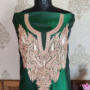 May include: A green silk kurta with a detailed gold and pink embroidery design around the neckline.