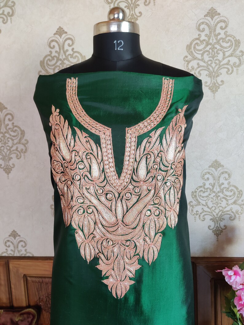 May include: A green silk kurta with a detailed gold and pink embroidery design around the neckline.