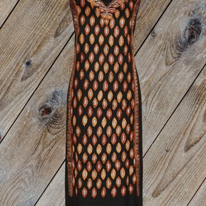 May include: A black long-sleeved dress with a V-neckline and a pattern of orange and gold leaves. The dress has a silver trim along the edges.