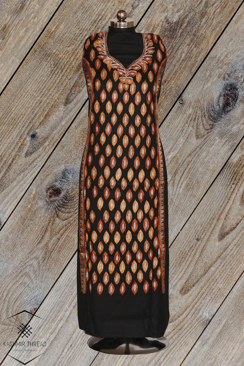 May include: A black long-sleeved dress with a V-neckline and a pattern of orange and gold leaves. The dress has a silver trim along the edges.