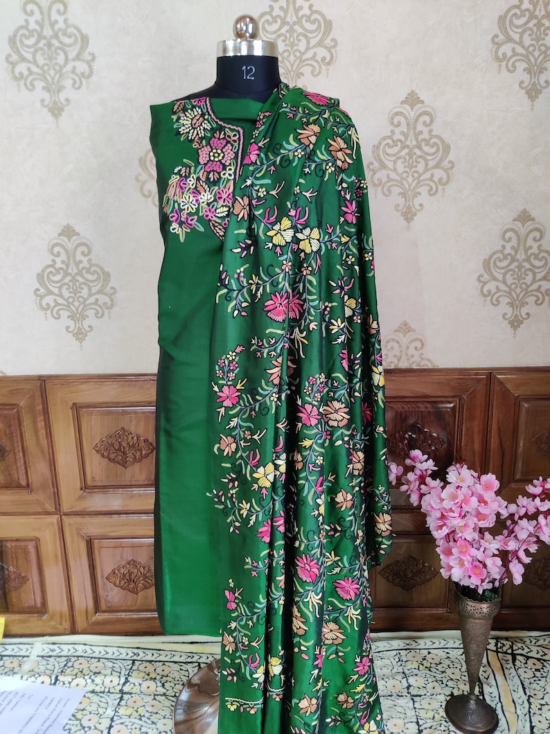 May include: A green embroidered dress with a floral pattern. The dress is on a mannequin and has a matching shawl.