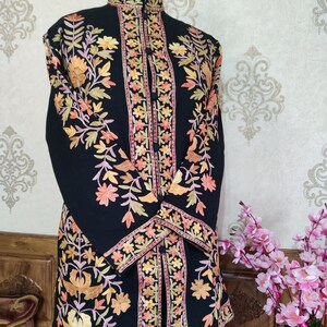 May include: A black long-sleeved jacket with intricate floral embroidery in shades of orange, pink, and green. The jacket has a mandarin collar and a button closure.