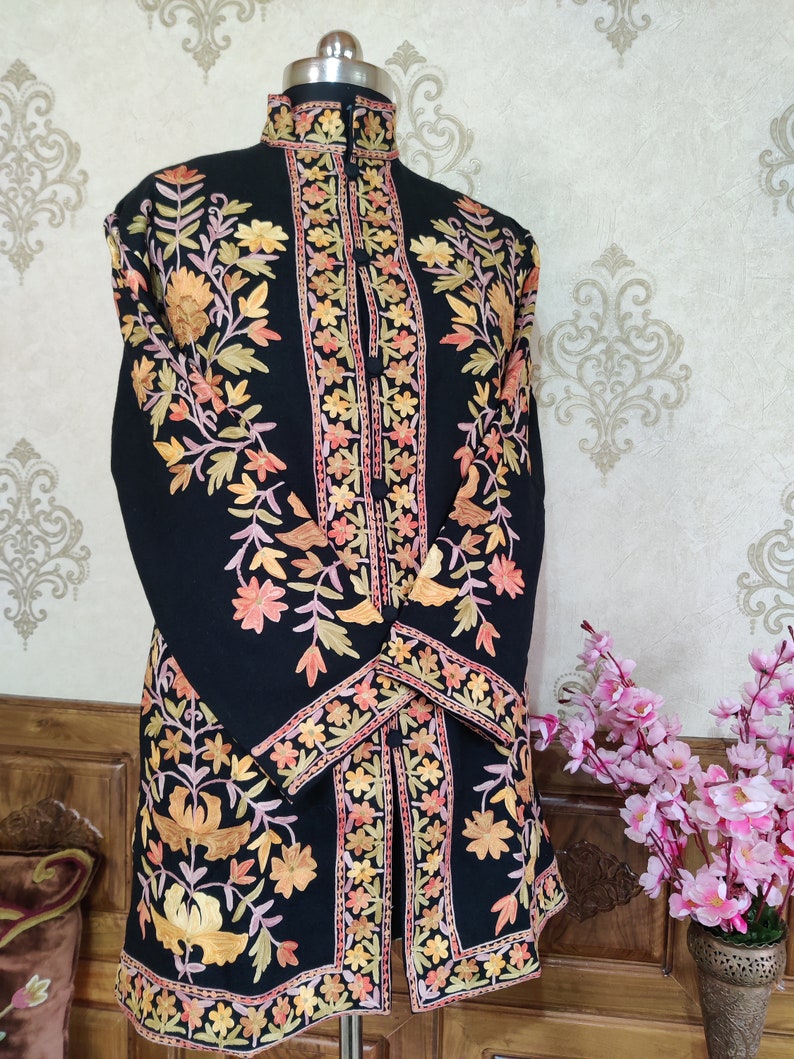 May include: A black long-sleeved jacket with intricate floral embroidery in shades of orange, pink, and green. The jacket has a mandarin collar and a button closure.
