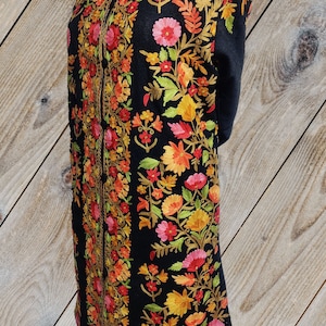 May include: A black long-sleeved shawl with intricate floral embroidery in shades of red, orange, yellow, and green.
