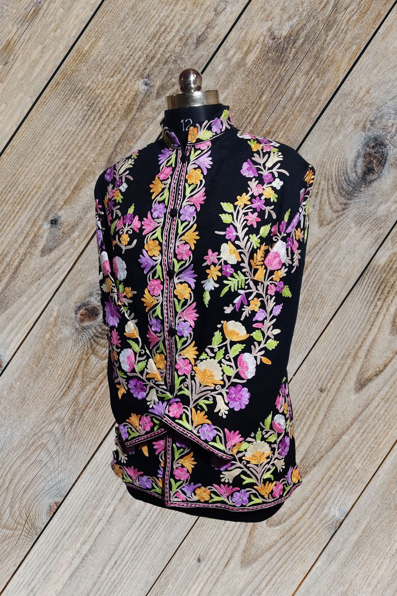 May include: A black long-sleeved shirt with a mandarin collar and intricate floral embroidery in shades of pink, purple, yellow, and green.