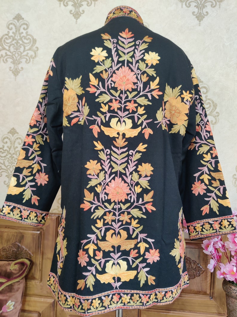 May include: A black embroidered jacket featuring a floral design in shades of orange, yellow, pink, and green. The jacket has a mandarin collar and long sleeves.