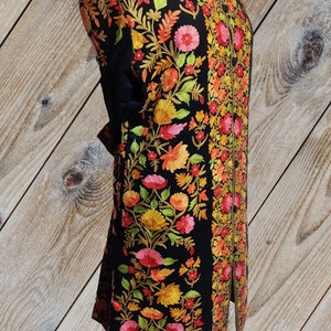 May include: A black long-sleeved jacket with intricate floral embroidery in shades of orange, yellow, pink, and green. The embroidery is done in a traditional style and covers the entire jacket.
