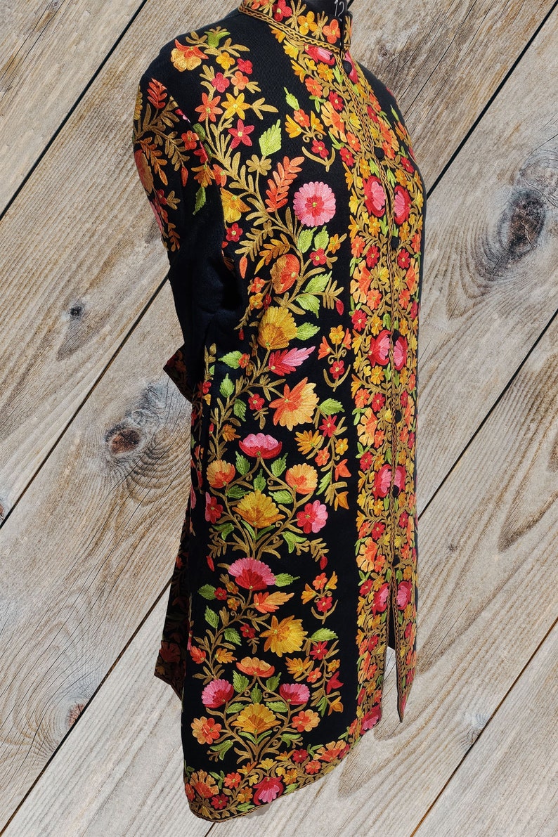 May include: A black long-sleeved jacket with intricate floral embroidery in shades of orange, yellow, pink, and green. The embroidery is done in a traditional style and covers the entire jacket.