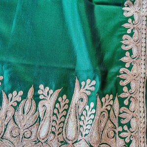 May include: A green fabric with a gold embroidered border. The embroidery features a floral design with paisley shapes.