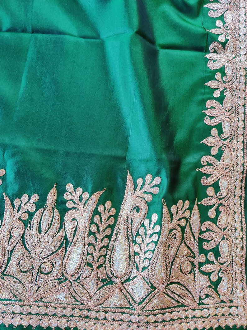 May include: A green fabric with a gold embroidered border. The embroidery features a floral design with paisley shapes.